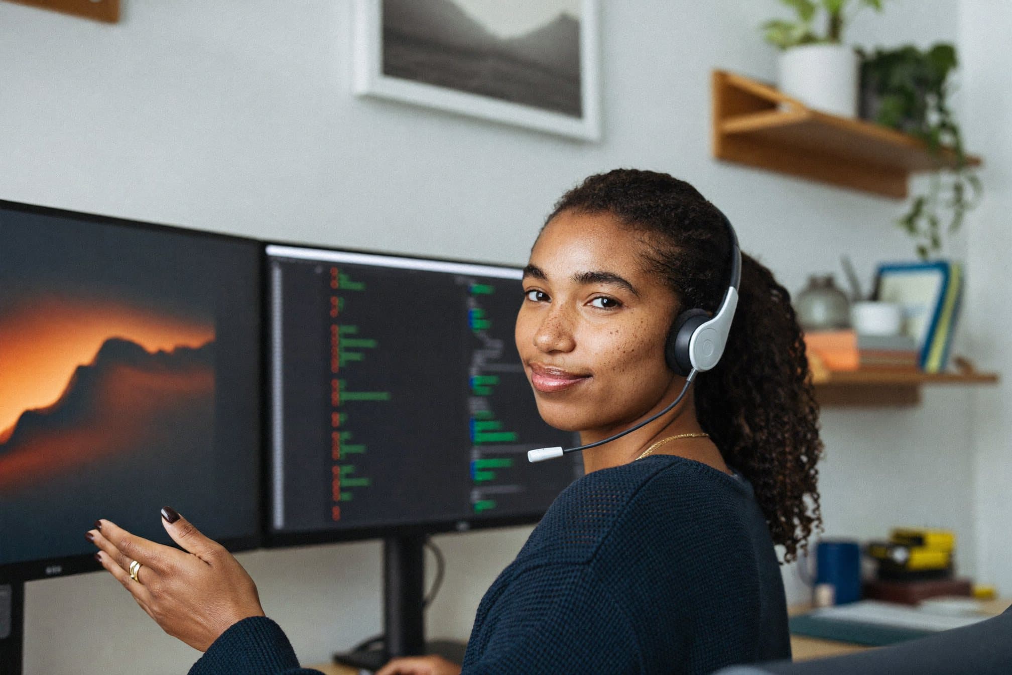 Une ingénieure support avec un casque se tourne vers la caméra, devant ses écrans